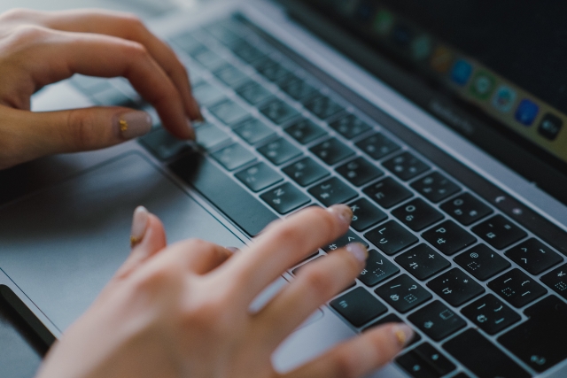 MacBookでタイピングする女性の両手